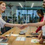 A diverse team of smiling professionals shaking hands during a productive meeting in a modern office.